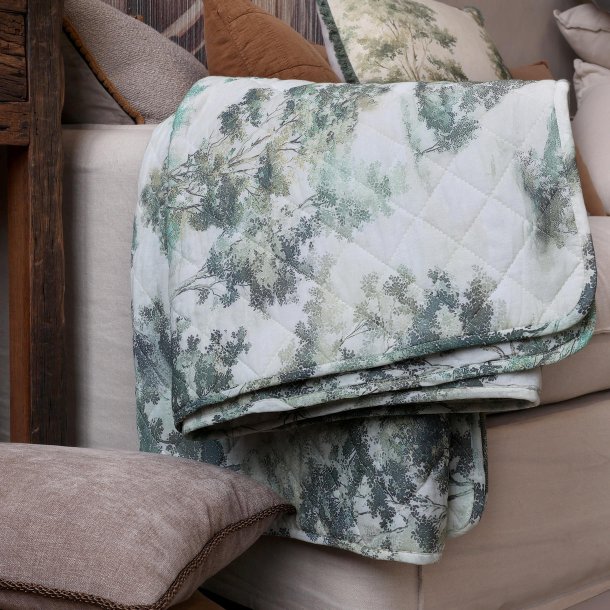 Quilt med landskabsprint i creme og oliven p� sofa